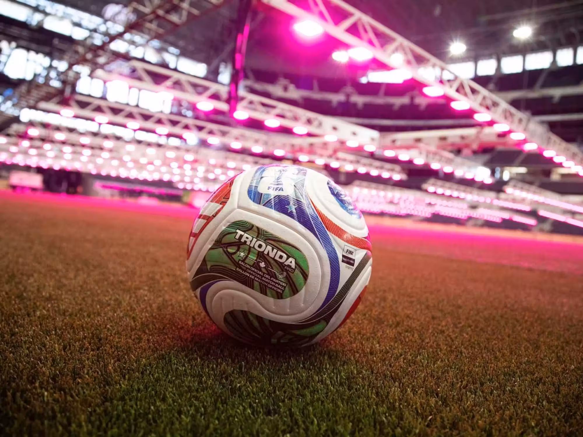 Trionda ball on the pitch of Dallas Stadium, highlighted by pink grow lights